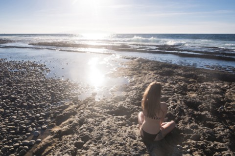 Caucasian woman sitting on beach wearing bikini