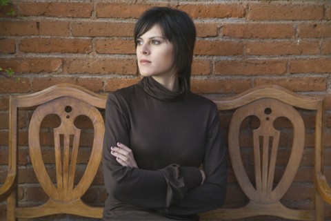 Frustrated Hispanic woman sitting on bench