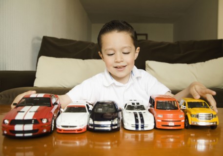 Hispanic boy lining up toy cars