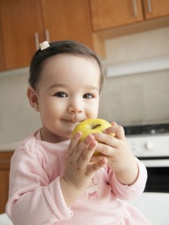 Hispanic baby girl eating apple