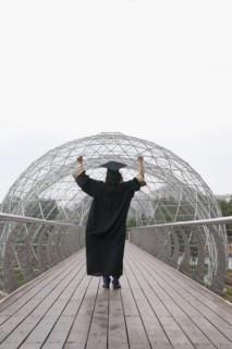 Mixed race graduate in cap and gown cheering