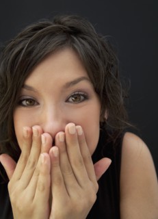 Surprised Hispanic woman with hands covering face