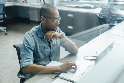 Black businessman using laptop behind window