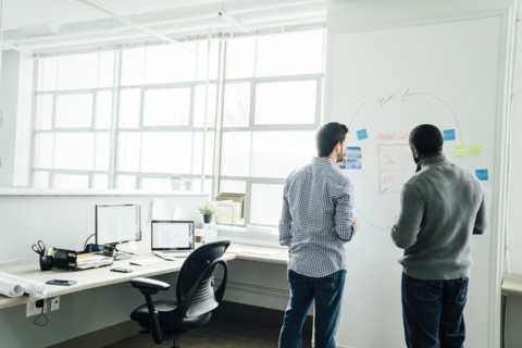 Businessmen using whiteboard in office