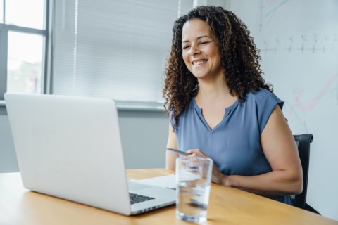 Mixed race businesswoman smiling at laptop