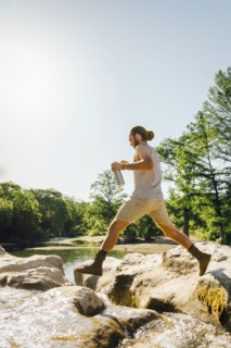 Caucasian man jumping on rocks near river