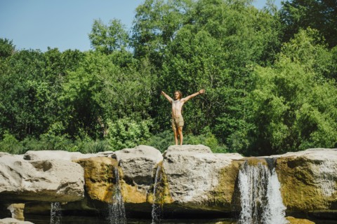 Caucasian man standing on rocks near waterfalls