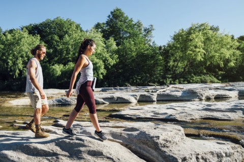 Caucasian couple walking on rocks near river