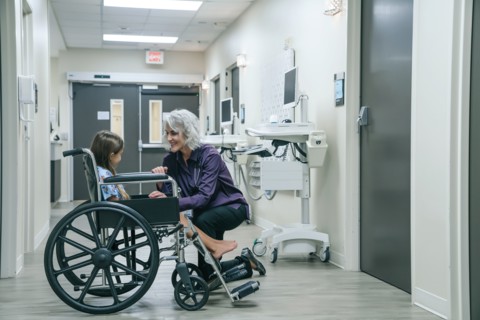 Smiling doctor comforting girl in wheelchair