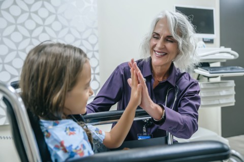 Doctor high-fiving girl in wheelchair
