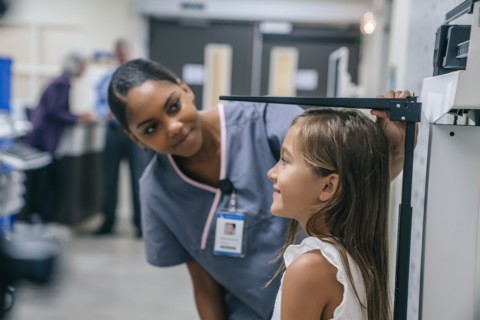 Nurse measuring height of girl
