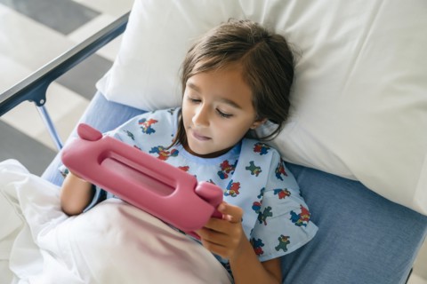 Mixed race girl using digital tablet in hospital bed