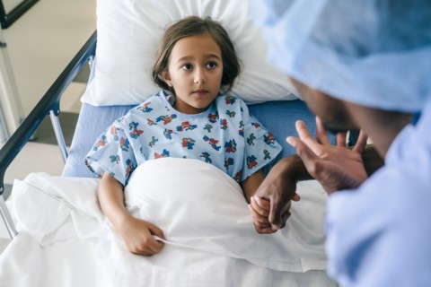 Nurse holding hands and talking to girl