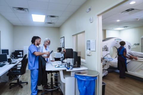 Doctor and nurse discussing digital tablet near scanner