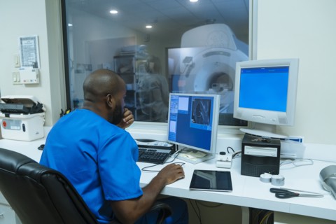 Black nurse using computer near scanner