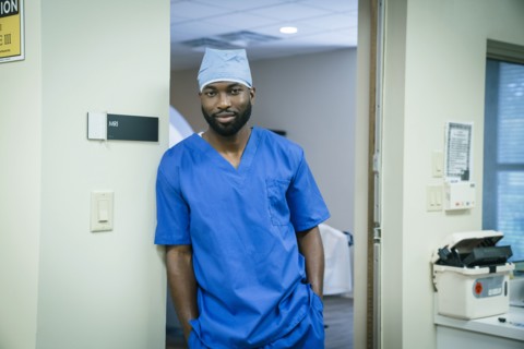 Portrait of a black nurse leaning in doorway