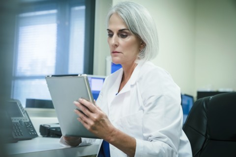 Serious Caucasian doctor using digital tablet