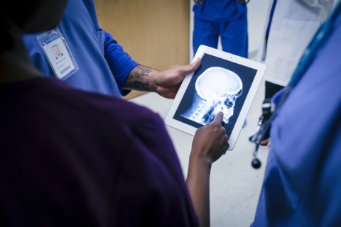 Doctors examining x-ray of skull and jaw on digital tablet