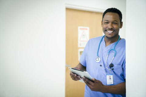 Portrait of smiling black nurse holding digital tablet