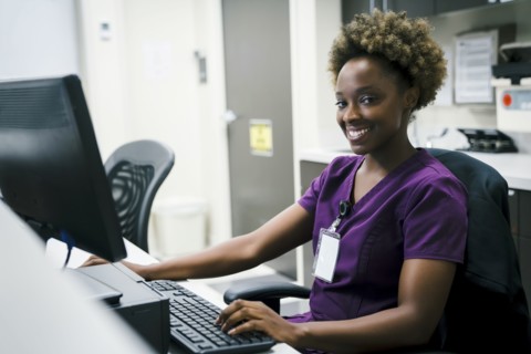 Portrait of smiling black nurse using computer