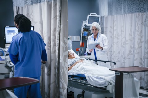 Doctor with digital tablet talking to patient in hospital bed