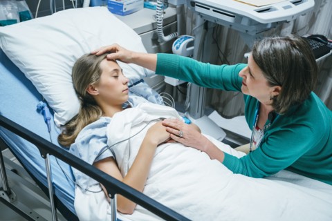 Caucasian doctor comforting patient in hospital bed