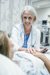 Caucasian doctor comforting girl in hospital bed