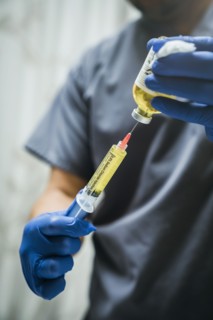 Mixed race nurse wearing rubber-gloves holding medicine and needle