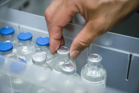 Hand of mixed race person holding vial of medicine