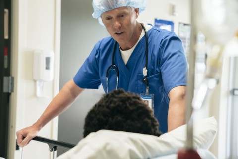 Doctor talking to boy in hospital bed