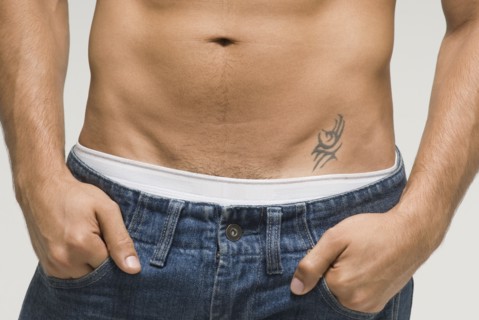 Bare-chested Hispanic man with hands in pockets