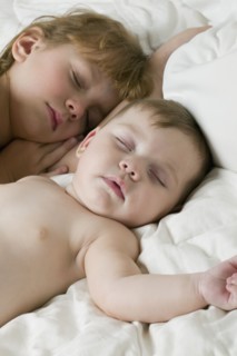 Young Hispanic siblings sleeping on bed