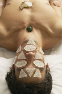 Hispanic man receiving stone and crystal spa treatment