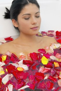 Hispanic woman with eyes closed in bath of flower petals
