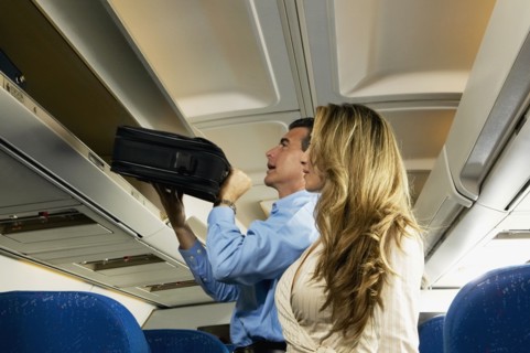 Couple stowing luggage in overhead compartment on airplane