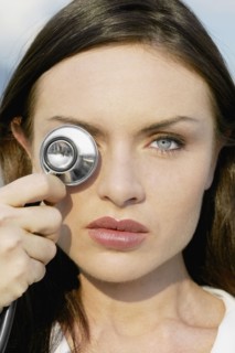 Close up of woman holding stethoscope over eye