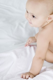Hispanic baby sitting on bed