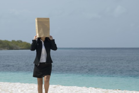 Hispanic businesswoman wearing bag over head