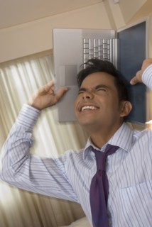 Hispanic businessman holding laptop around head