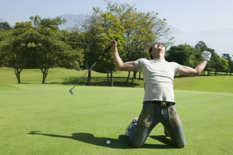 Asian man cheering on golf course
