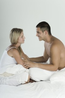 Smiling Hispanic couple sitting in bed