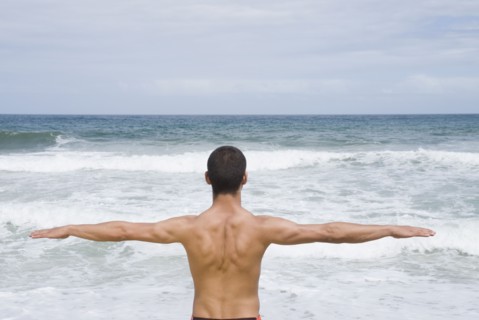 Hispanic man with arms out at beach