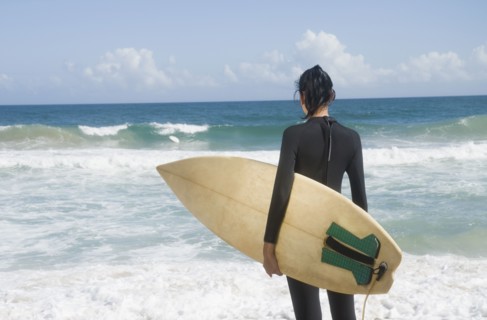 Hispanic woman at beach with surfboard