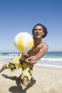 African man playing volleyball at beach