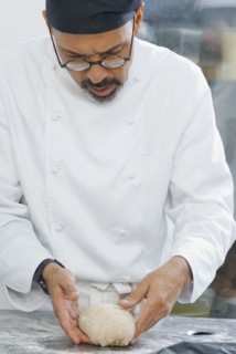 Baker working with dough in bakery kitchen