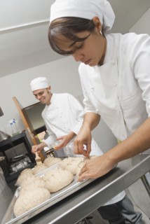 Bakers working with dough in bakery kitchen
