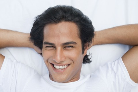 Smiling Hispanic man laying in bed