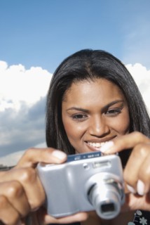 Black woman taking photograph with digital camera