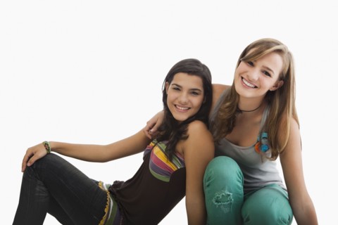 Smiling Hispanic sisters hugging