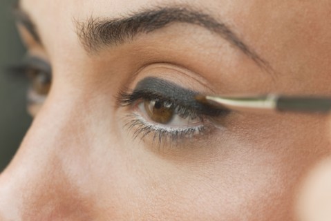Caucasian woman putting on eyeliner